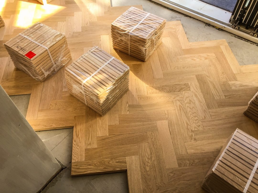 packs of wooden parquet flooring are seen during installation of wood herringbone kitchen floor