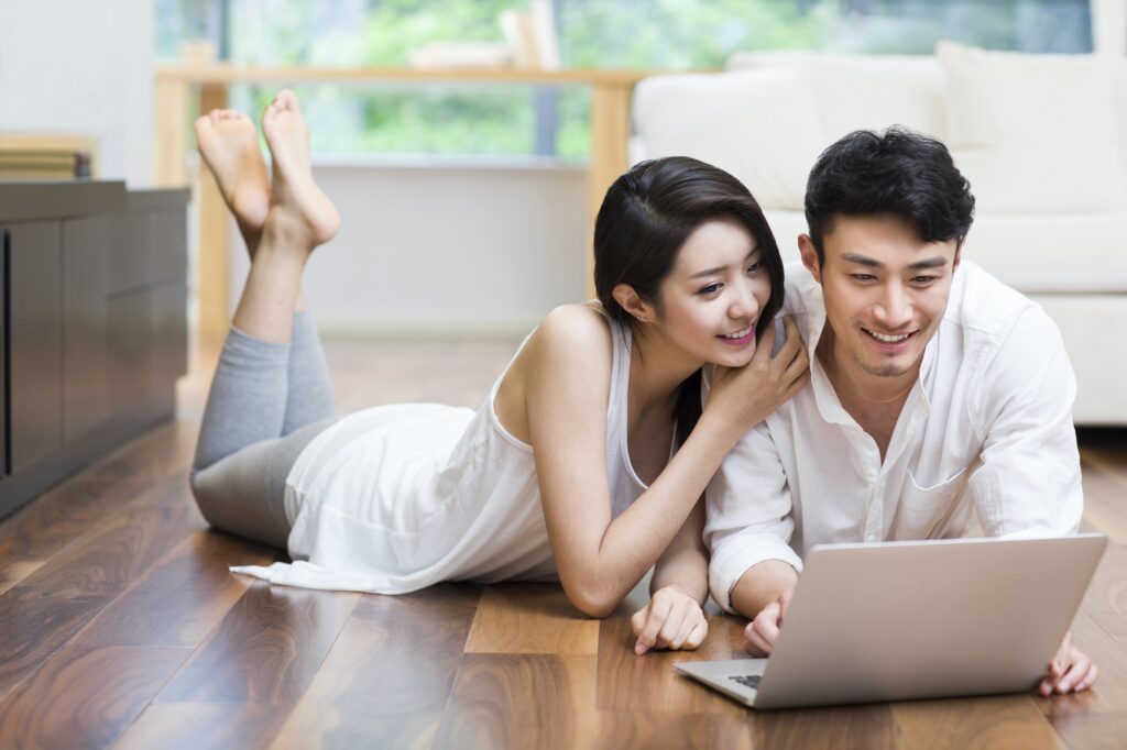 Young couple lying on floor using laptop